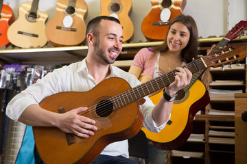 Obraz premium couple choosing acoustic guitar