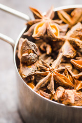 Dried anise stars in metal cup on the rustic background. Selective focus. Shallow depth of field.