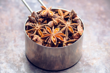Dried anise stars in metal cup on the rustic background. Selective focus. Shallow depth of field.