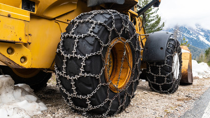 Front loader for snow removal with metal snow chains on wheels. Snow removal in the mountains.