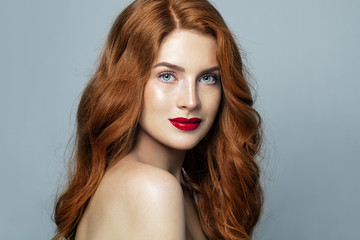 Pretty red haired woman studio portrait. Redhead girl smiling