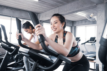 Fototapeta na wymiar Attractive young women working out together on exercise bike at the gym.