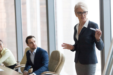 Confident middle-aged mentor speaking giving presentation at executive team training