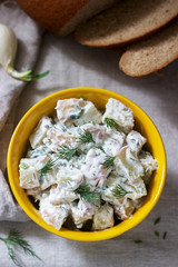Traditional cold potato salad with onions and herbs on a linen tablecloth background. Rustic style.