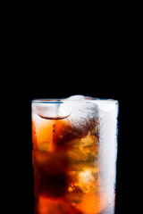 Cold cola beverage in glass with ice isolated on black background. Selective focus. Shallow depth of field.