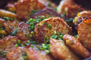 freshly made rustic potato pancakes (draniki) with greens close-up