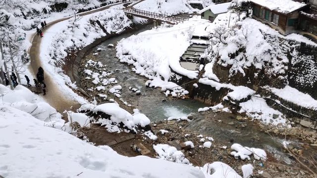 A slow pan showing the beautiful landscape of a valley covered in snow at Yamanouchi in Nagano, Japan where the famous 'Jigokudani Monkey Park' is located. Jigokudani means "hell valley".