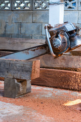 Carpenter is using gasoline engine portable chainsaw cut timber.