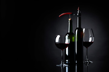 Red wine with corkscrew on a black background.