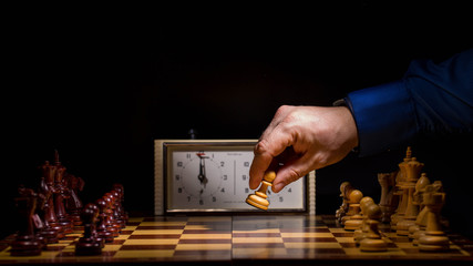 Detail of chess competition. Mans hand making the first move in a chess game, moving the pawn one field forward. Selective focus