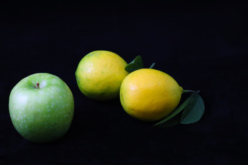 Fototapeta na wymiar Qreen apple and lemons on black background 