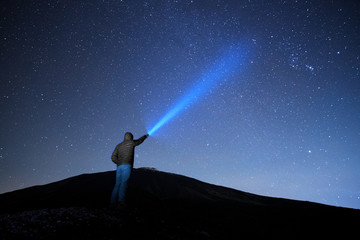 Man Pointing Blue Flashlight To Starry Sky - obrazy, fototapety, plakaty