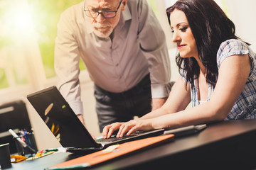 Young businesswoman and senior businessman working together, light effect