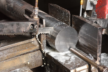 The process of cutting metal with an electric saw in a factory. Electric saw cuts round metal