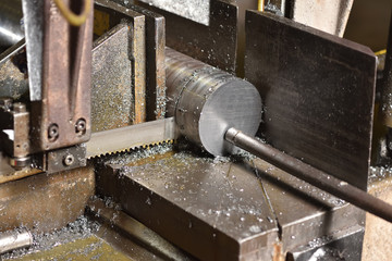 The process of cutting metal with an electric saw in a factory. Electric saw cuts round metal
