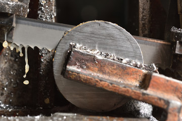 The process of cutting metal with an electric saw in a factory. Electric saw cuts round metal