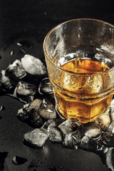 Whiskey and ice on rustic wood background