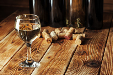 Fototapeta na wymiar Wine bottles with glass, wooden background