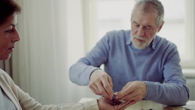 Senior couple with wheelchair sitting at the table at home, taking drugs and pills.