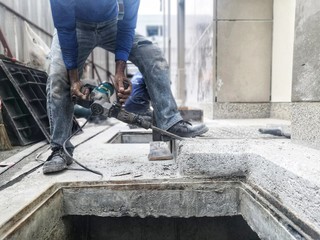 The construction worker is drilling the floor. Construction technicians use electric hammer chisels to destroy the ground