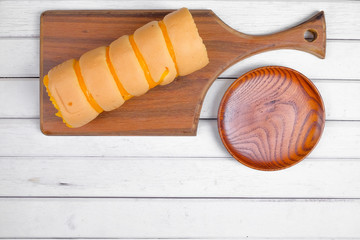 Roll cake  butter cream filling and  wooden plate on wooden plate over white wooden background
