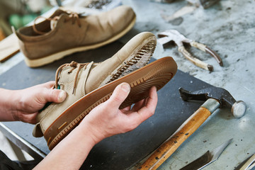 Shoemaker repair shoe. Glueing the sole for male footwear - obrazy, fototapety, plakaty