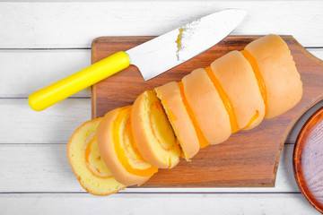 Roll cake  butter cream filling and on wooden plate over white wooden background