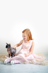 A girl in a pink dress with a bald cat