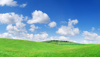 Obraz premium Idyllic view, green hills and blue sky with white clouds