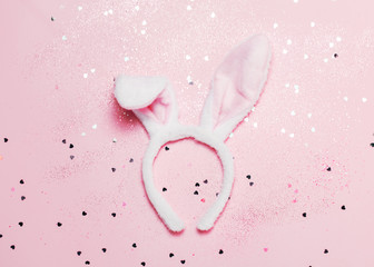 Top view and flat lay of Easter symbol - bunny ears on pink background. Festive and bright, confetti and sparks.