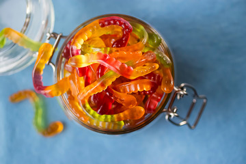 Chewing marmalade in the form of worms in a glass jar. Gummies.