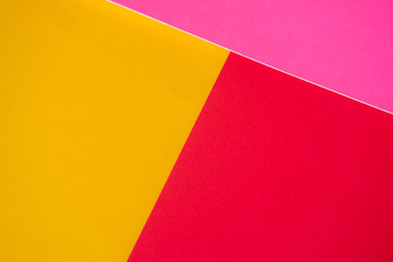 Textured triangles of yellow, red and pink colors. Design paper.