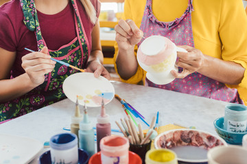Women in DIY workshop coloring and decorating their own ceramic