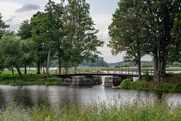 Fototapeta na wymiar Old narrow bridge with stone pillars ina green environment