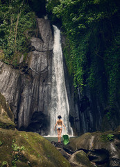 A girl in a swimsuit at the waterfall. Air Terjun Kuning Waterfall in Bali. Bali trip. Travel.