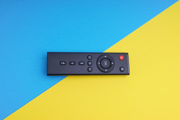 Fototapeta premium Remote control TV or radio on blue and yellow background with selective focus and crop fragment