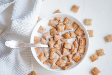 Dry breakfast cereal pads with milk on a white concrete background