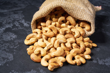 Cashew nuts are poured out of the bag on a black table,Close-up