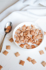 Dry breakfast cereal pads with milk on a white concrete background