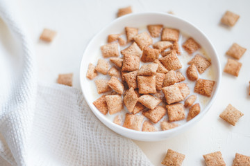 Dry breakfast cereal pads with milk on a white concrete background