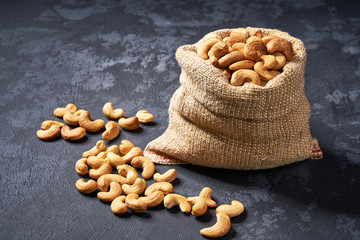 Cashew nuts  in burlap sack on black table. Heap or stack of cashew nuts .