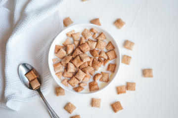 Dry breakfast cereal pads with milk on a white concrete background