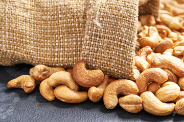 Cashew nuts  in burlap sack on black table.