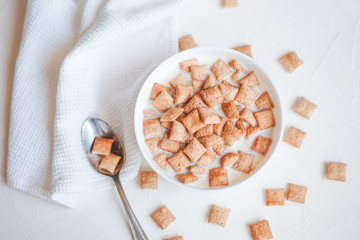 Dry breakfast cereal pads with milk on a white concrete background