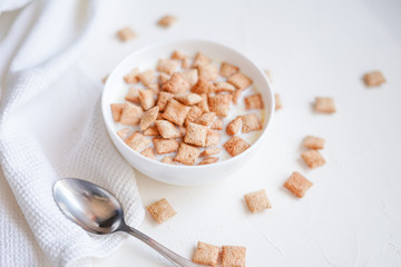 Dry breakfast cereal pads with milk on a white concrete background