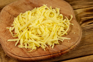 Grated cheese on cutting board on wooden table