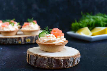Tartlets with cream cheese and salted salmon on black background. Tasty light snack for a party. Finger Food.