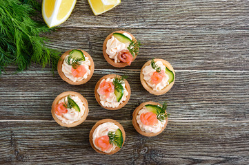 Tartlets with cream cheese and salted salmon on a wooden background. Tasty light snack for a party. Finger Food. The top view.