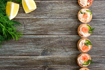 Tartlets with cream cheese and salted salmon on a wooden background. Tasty light snack for a party. Finger Food. The top view with copy space