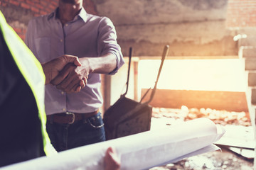 engineer working on checking progress of construction with blueprint at construction site